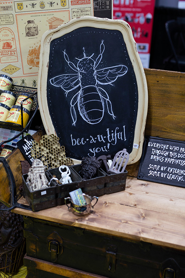 A chalkboard with a bee drawn on it beside iron trinkets