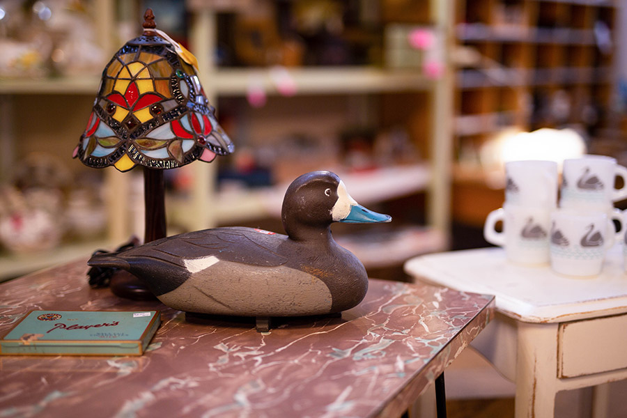 A painted wooden duck beside a stained glass lamp